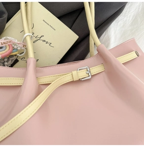 Detail of pink faux leather tote bag with silver buckle and decorative lace floral charm