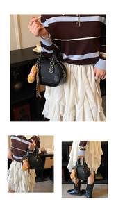 Detail of black crossbody bag featuring gold hardware and plush doll pendant ornament