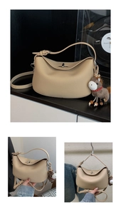Detailed shot of beige lychee leather underarm bag with metal lock and horse charm