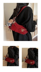 Detailed close-up of a red saddle bag with golden buckles and a small teddy bear charm