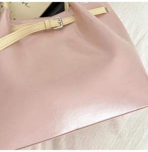 Detailed view of pink tote bag with beige strap decoration and silver metal buckle