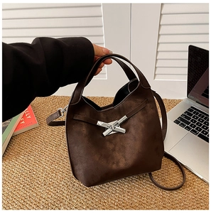 Détail du sac seau marron foncé avec fermoir en métal en X et texture en daim doux