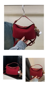 Detail of burgundy shoulder bag with round flap, gold clasp, and cute pony charm accessory