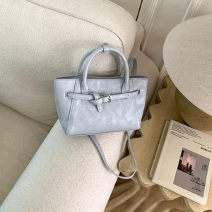 Close-up of minimalist light blue crossbody bag with silver buckle and leather texture