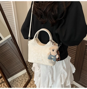 Détail du sac vintage crème avec plaque logo argentée et breloque ours en peluche