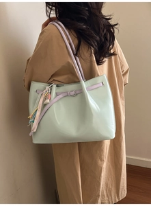 Detail of mint green leather tote bag with colorful charms and beaded strap accents