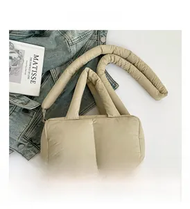 Detail of beige quilted puffer tote bag with vertical stitching and wide handle strap