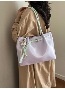 Detail of light purple tote bag with mint green straps and rainbow charm accessory