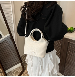 Gros plan du sac en cuir crème avec poignée et bandoulière dans un décor intérieur moderne