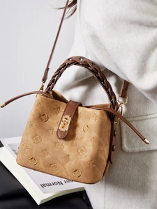 Vintage embossed bucket bag with woven handle and gold clasp on a white coat model