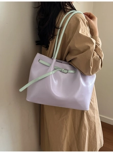Close-up of a purple faux leather tote with green straps and contrast buckle detail