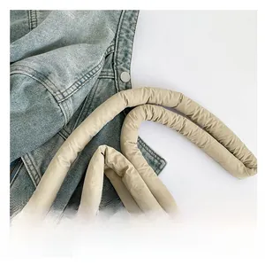 Detail of padded shoulder strap on beige nylon tote bag with soft cushioned texture
