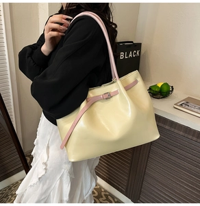 Detailed side view of a large cream tote bag with pink handles worn by a model