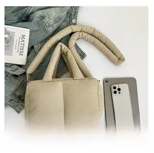Detailed size comparison of beige quilted puffer tote bag with a smartphone and art book