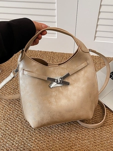 Sac seau beige élégant avec boucle métallique et bandoulière dans un cadre de bureau