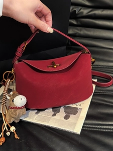 Red leather underarm bag with gold metal buckle and horse charm accessory