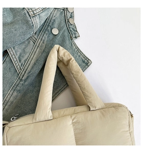Close-up of quilted padded tote bag in cream nylon with silver zipper and soft handle