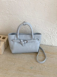 Light blue faux leather handbag with decorative strap and crossbody shoulder strap
