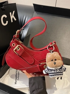Fashionable red leather saddle bag with gold hardware and plush dog pendant charm