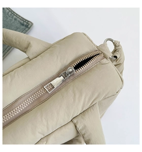 Detail of silver heavy-duty zipper and quilted padded fabric on beige tote bag