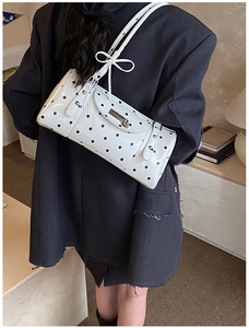 Detail of white polka dot shoulder bag with decorative bows and silver metallic studs