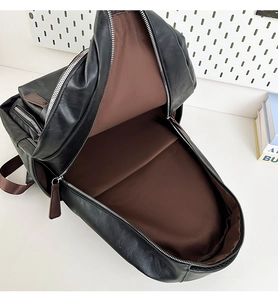 Macro view of a large black PU leather backpack with silver zippers and brown lining