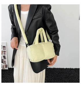 Detail of light yellow quilted puffer bag featuring soft padding and wide shoulder strap