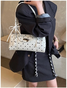 Close-up of polka dot underarm bag with bow decoration and shiny patent leather