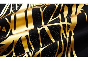 Détail macro du tissu noir avec feuille d'or et strass noirs sur le motif de cheval