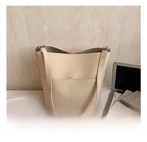 Detail of beige lychee leather bucket bag with vertical stitching and shoulder strap