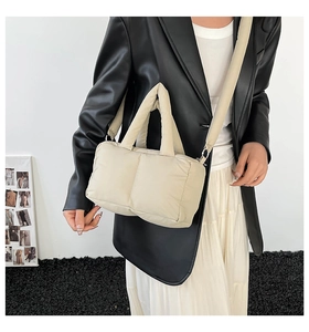 Detail of soft quilted puffer tote bag with adjustable strap worn by model in beige