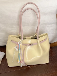 Large cream leather tote bag with pink straps and a colorful rainbow charm decoration