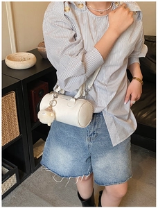 Detail of white cylindrical crossbody bag with plush lamb charm and fashion lettering