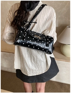 Close-up of retro black polka dot shoulder bag featuring silver rivets and metal buckle