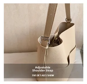 Detail of adjustable strap with silver buckle on beige pebbled leather bucket bag