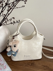 Sac à main en cuir texturé blanc crème avec breloque ours en peluche sur bois