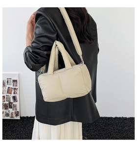 Detail of soft quilted puffer tote bag in beige with adjustable shoulder strap and padded handle