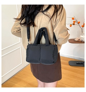 Back view of a black quilted puffer tote bag shown on model in a modern interior
