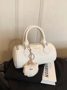 Fashionable cream white boston bag in glossy patent leather with a plush monster pendant