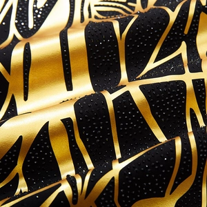 Détail macro du tissu noir avec motifs géométriques dorés et strass noirs de haute qualité
