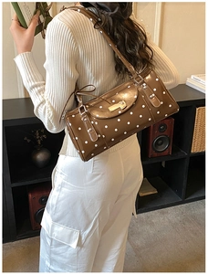 Detail of vintage brown polka dot shoulder bag with glossy leather and gold buckle