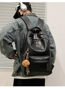 Detail of black PU leather backpack with zippers and a cute brown puppy plush keychain