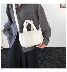 Detail of white quilted puffy tote bag featuring soft padded straps and side metal hook