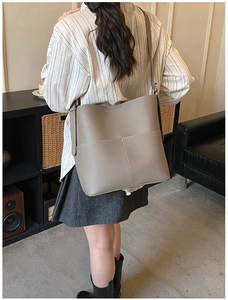 Taupe large capacity bucket bag with wide strap shown on model in home setting