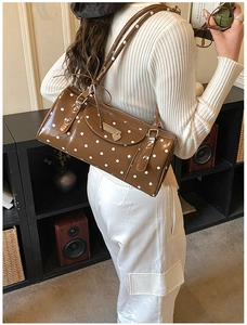 Close-up of brown polka dot handbag with glossy finish and heart charm detail