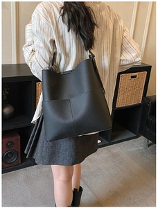 Close-up of black leather bucket bag with cross stitching detail and outer pockets