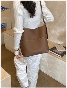 Close-up of brown pebbled leather tote bag with decorative stitching and adjustable strap