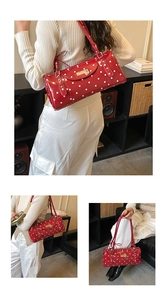 Détail d'un sac polochon rouge à pois en cuir verni brillant avec des finitions métalliques