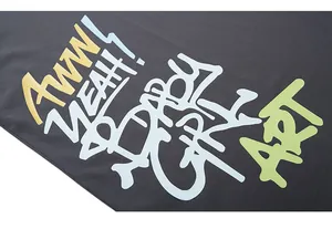 Close-up of graffiti lettering and premium cotton fabric texture on dark grey streetwear T-shirt