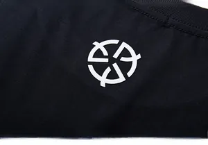 Close-up of the white circular geometric logo printed on black heavy cotton T-shirt fabric